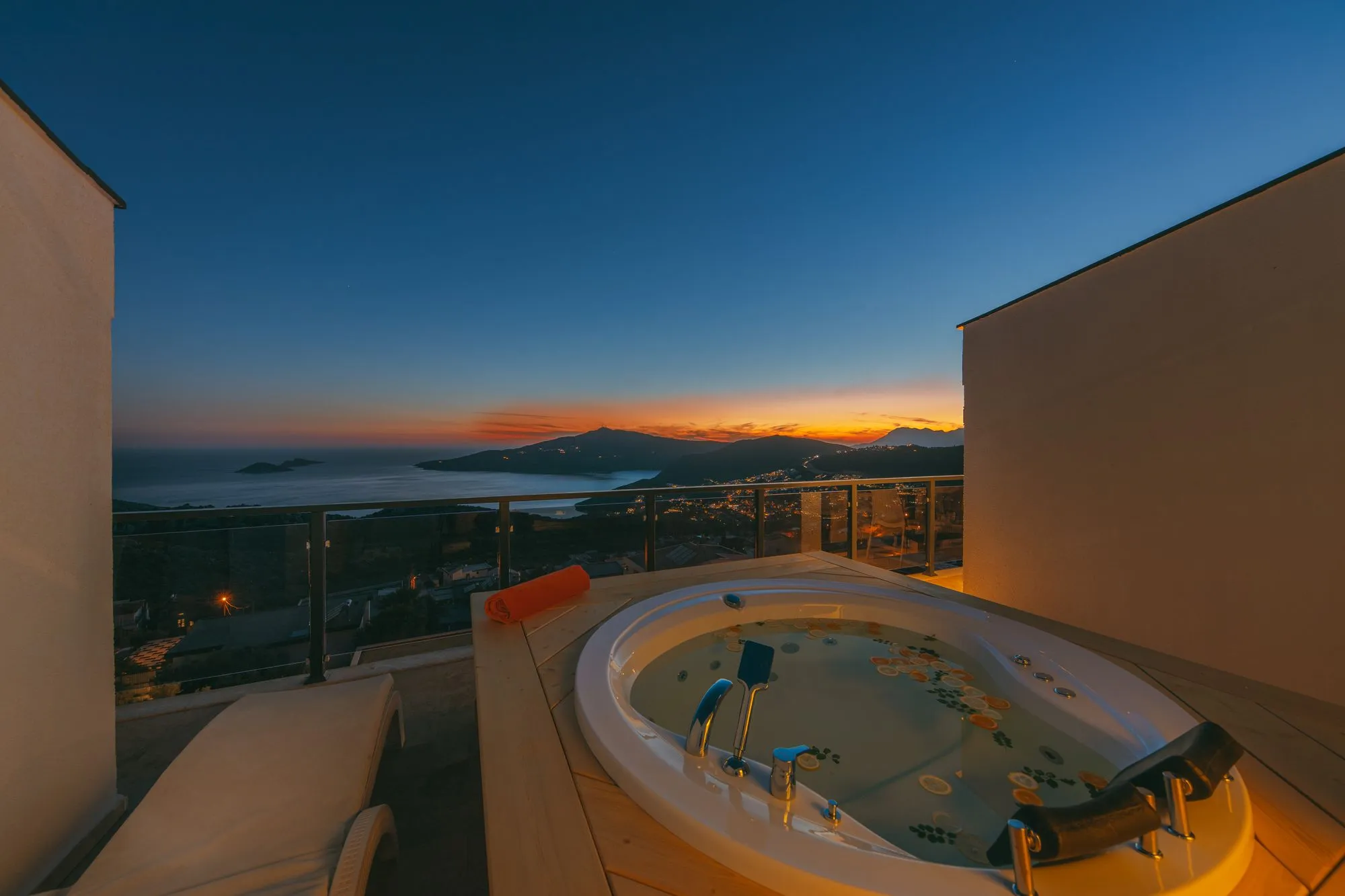 Spa encastré sur une terrasse blanche face à la mer, au coucher du soleil